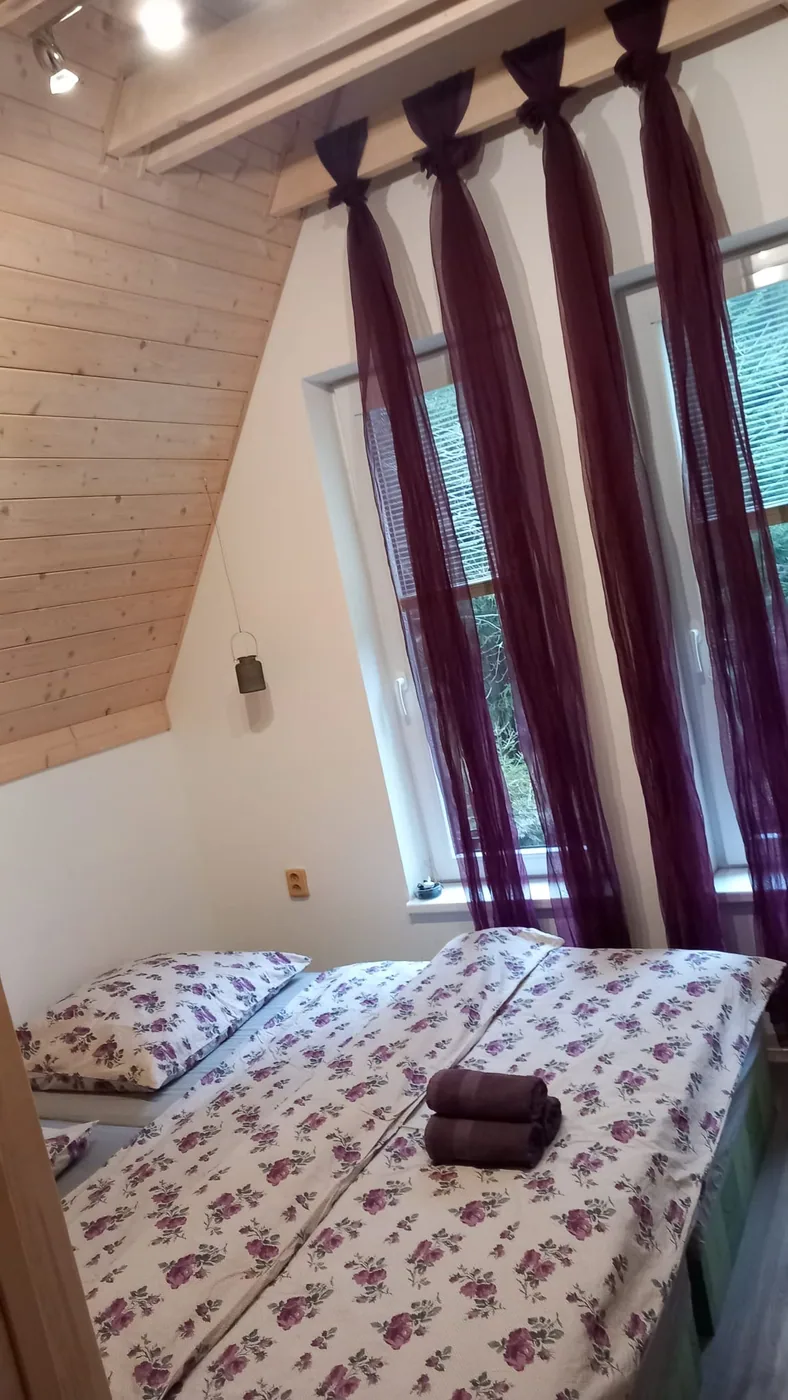 Ložnice s manželskou postelí a dřevěným stropem